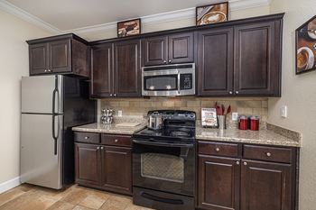 Chef's kitchen with stainless steel appliances and espresso wood cabinetry - DeLayne at Twin Creeks